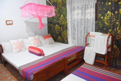 a small bedroom with a bed and a pink umbrella at S P City Resort in Anuradhapura