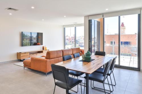 a living room with a table and a couch at Indulge Apartments - City View Penthouses in Mildura