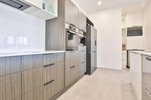 a kitchen with wooden cabinets and stainless steel appliances at Indulge Apartments - City View Penthouses in Mildura
