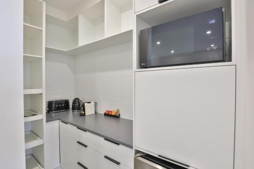 a kitchen with white cabinets and a refrigerator at Indulge Apartments - City View Penthouses in Mildura
