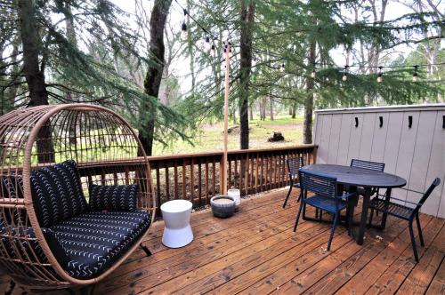 drewniany taras ze stołem i krzesłami oraz rattanową huśtawką w obiekcie Gnome and Creek Yosemite Condo w mieście Groveland