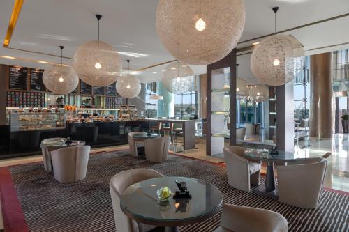a restaurant with tables and chairs and chandeliers at Park Rotana Abu Dhabi in Abu Dhabi