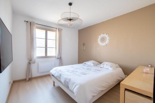 een witte slaapkamer met een bed en een raam bij Le Saint-Clémentois - Maison pour 6 in Saint-Clément