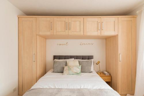 a bedroom with a large white bed with wooden cabinets at Surrey Stays - 2 Bedroom House, RH1, Contractors Welcome, Sleeps 5 max, 2 Parking Spaces, Near Town Centre, Train Station and Gatwick Airport in Redhill