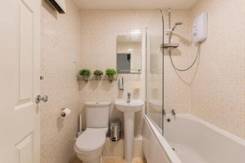 y baño con aseo, lavabo y ducha. en Surrey Stays - 2Bed house, 2 parking spaces, RH1, near Gatwick Airport, en Redhill
