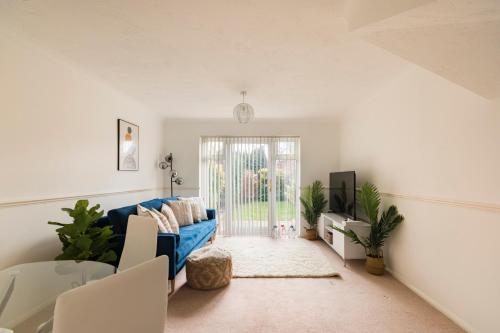 a living room with a blue couch and a sliding glass door at Surrey Stays - 2 Bedroom House, RH1, Contractors Welcome, Sleeps 5 max, 2 Parking Spaces, Near Town Centre, Train Station and Gatwick Airport in Redhill