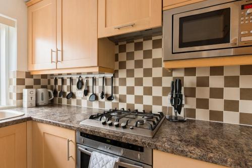 a kitchen with a stove and a microwave at Surrey Stays - 2 Bedroom House, RH1, Contractors Welcome, Sleeps 5 max, 2 Parking Spaces, Near Town Centre, Train Station and Gatwick Airport in Redhill