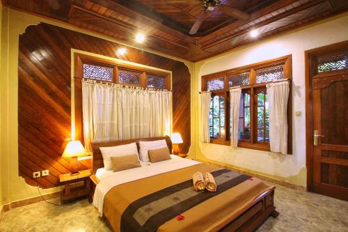 a bedroom with a bed and two shoes in it at Hibiscus Cottages in Ubud