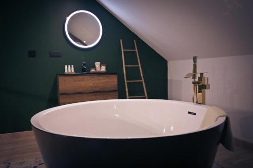 a large bath tub in a green bathroom with a mirror at Maison avec jacuzzi privatif in Renac