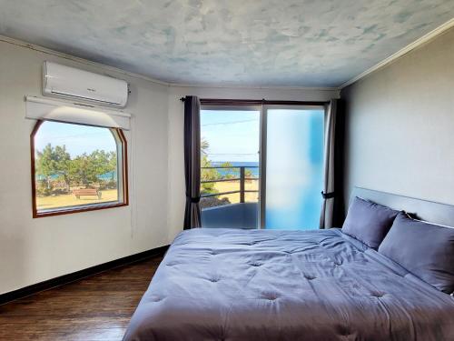 a bedroom with a bed and a large window at The House Pension in Jeju