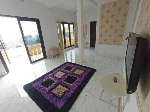 a living room with a purple rug and a tv at RD Cottage Valley in Bogor