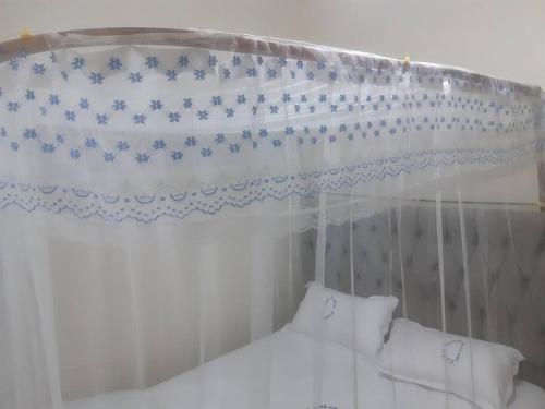 uma cama de dossel branco com uma cortina azul e branca em LaMeg Homestay em Nairobi