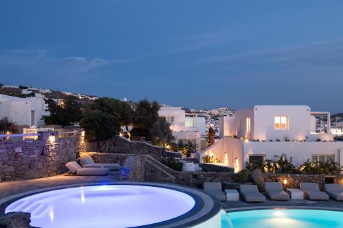 a view of a swimming pool at night with white buildings at Porto Mykonos in Mikonos