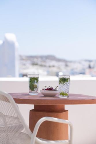 a wooden table with two glasses and a plate on it at Porto Mykonos in Mýkonos City