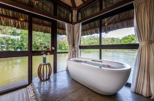 a bath tub in a room with large windows at Vinpearl Resort & Spa Phu Quoc in Phú Quốc