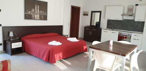 ein Schlafzimmer mit einem roten Bett und einem Tisch sowie eine Küche in der Unterkunft Residence San Prospero in Garbagnate Milanese