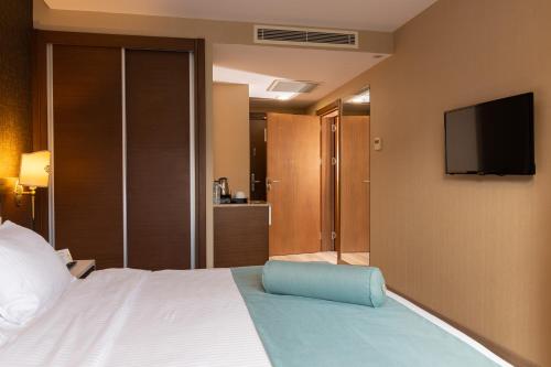 a hotel room with a bed and a flat screen tv at Tilya Resort Hotel in Trabzon