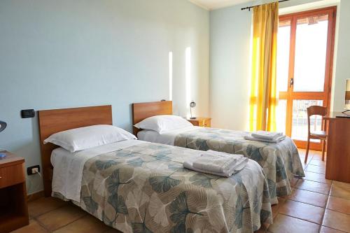 a bedroom with two beds and a window at Al Casale B&B in Cherasco