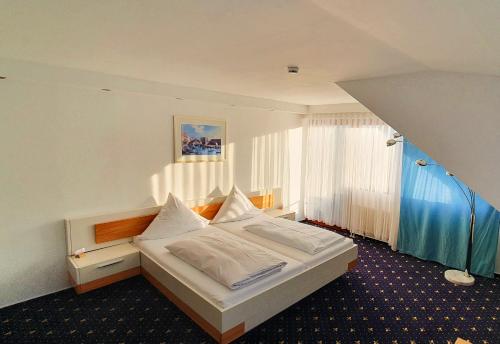 Schlafzimmer mit einem Bett mit weißer Bettwäsche und einem Fenster in der Unterkunft Schwaben Hotel Ebnisee in Ebni