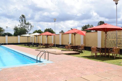 a swimming pool with tables and umbrellas and chairs and a pool at LaMeg Homestay in Nairobi