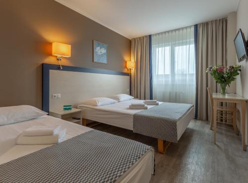 a hotel room with two beds and a window at Aurora Hotel Klaipeda in Klaipėda