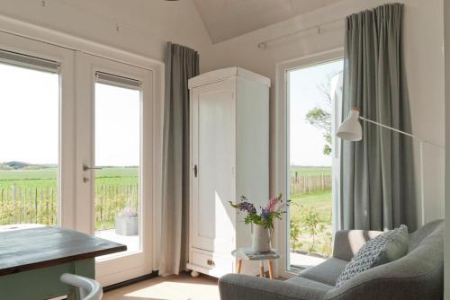 ein Wohnzimmer mit einem Sofa, einem Tisch und Fenstern in der Unterkunft Vakantieverblijf de Trommel in Domburg