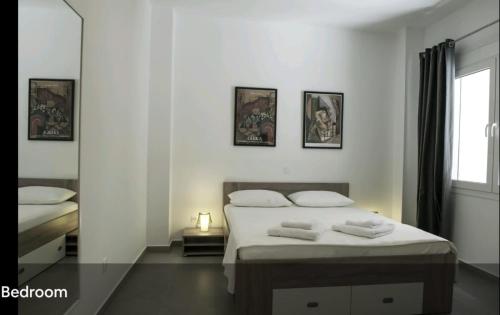 a white bedroom with two beds and a window at SYNTAGMA VOULIS STREET MODERN APARTMENT in Athens