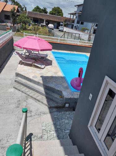 una piscina con una sombrilla rosa y un cisne rosa en Apto com piscina 3 quartos 500m do mar praia Ubatuba en São Francisco do Sul