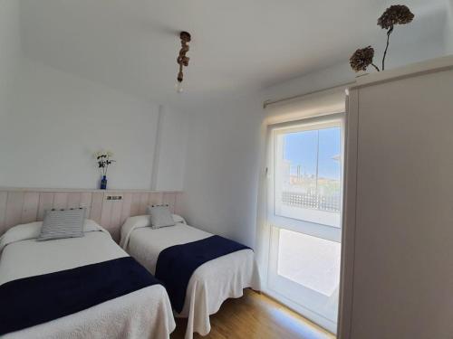 two beds in a room with a window at El Rincón de Gabriela in Suances