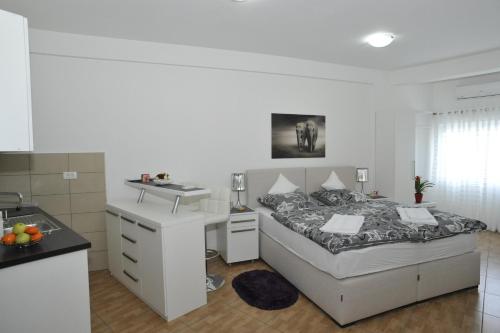 ein weißes Schlafzimmer mit einem Bett und einem Waschbecken in der Unterkunft Apartment Jovana Nikšić in Nikšić