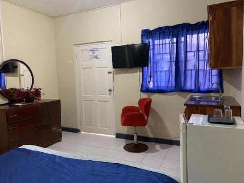 um quarto com uma cama e uma cadeira vermelha em Relax in Jamaica - Enjoy 7 Miles of White Sand Beach! villa em Negril