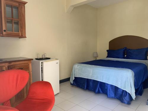 尼格瑞爾的住宿－Relax in Jamaica - Enjoy 7 Miles of White Sand Beach! villa，一间卧室配有一张床和一张红色椅子