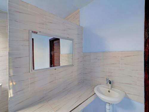 a white bathroom with a sink and a mirror at OYO 92401 Hotel Mustika in Mendaya
