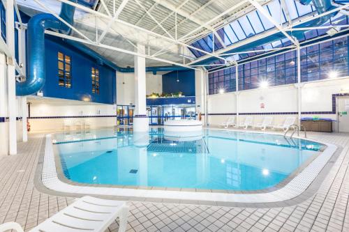 a large swimming pool with blue water in a building at Holiday Inn London Sutton, an IHG Hotel in Sutton