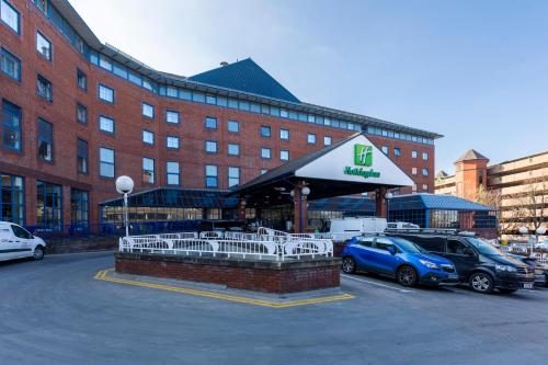 a parking lot with cars parked in front of a building at Holiday Inn London Sutton, an IHG Hotel in Sutton
