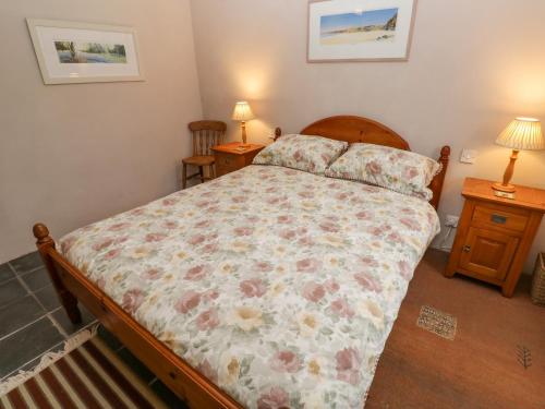 a bedroom with a bed and two night stands at Swallows in Saint Keverne