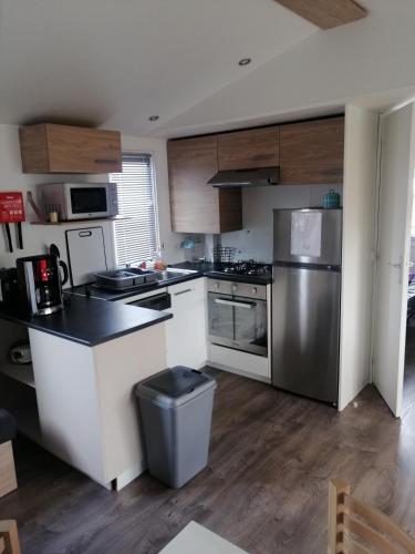 a kitchen with white cabinets and a stainless steel refrigerator at MHVACANCES LOUENT PLUSIEURS MOBILHOMES DANS CAMPING 4 ETOILES PROCHE CHATEAUX et ZOO BEAUVAL in Onzain
