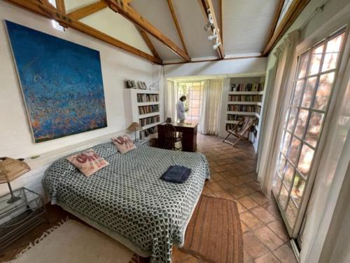 a bedroom with a large bed in a room with windows at Weaver Cottages in Harare