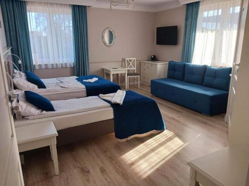 a bedroom with two beds and a blue couch at Willa Aura Mare in Dziwnów