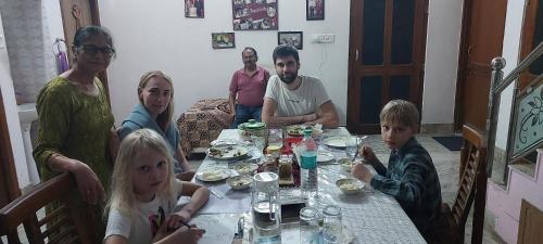 a family sitting around a table eating food at Travel curiosity Homestay in Alwar