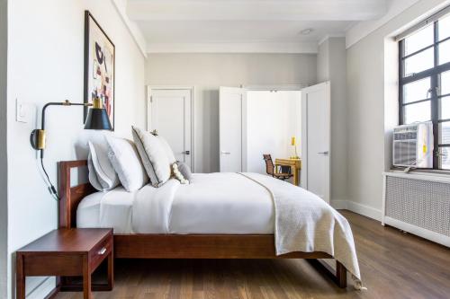 a bedroom with a bed with white sheets and a window at New W Village 2BR w WD Doorman nr Bars NYC-553 in New York