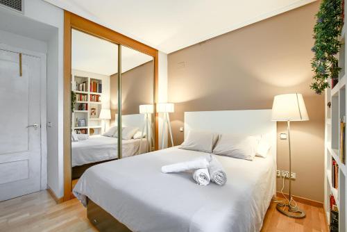 1 dormitorio con 1 cama blanca grande y espejo en Apartamento en Chamberí con piscina - Lovely apartment in the City Center with swimming pool, en Madrid