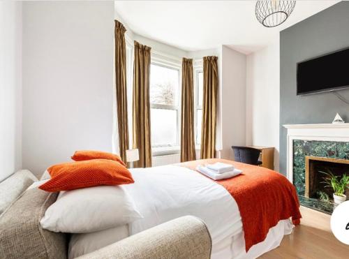 a bedroom with a bed with an orange blanket and a fireplace at Cozy private room in London