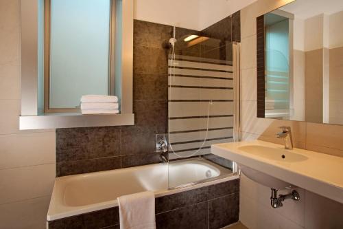 bagno con vasca, lavandino e specchio di Hotel Artis a Roma