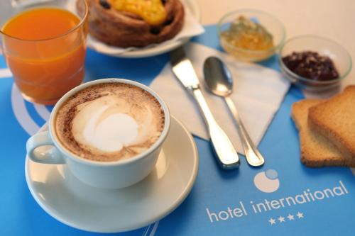 a cup of coffee on a plate on a table at International Hotel & Suite in San Benedetto del Tronto