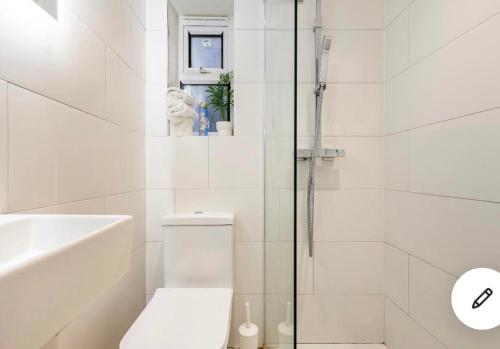 a white bathroom with a toilet and a shower at Cozy private room in London