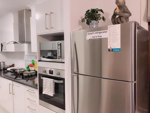 a stainless steel refrigerator in a white kitchen at Home Away From Home-(Room1) in Gold Coast