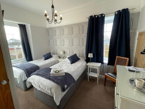 a bedroom with two beds and a chandelier at The Brookfield in Braunton