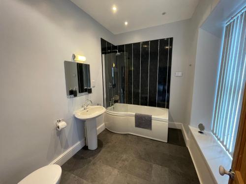 a bathroom with a toilet and a tub and a sink at The Brookfield in Braunton