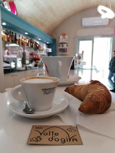 een tafel met een kopje koffie en een croissant bij Antica Dimora B&B VOLTE D'OGIVA in Altamura